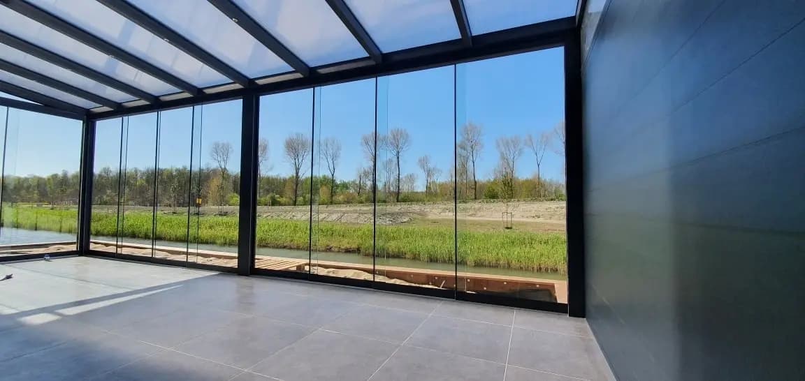 Uitzicht vanuit een veranda door glazen schuifwanden over een weiland