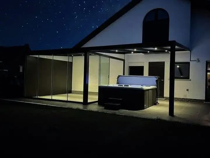 Veranda met glazen wanden en een jacuzzi, ’s avonds verlicht