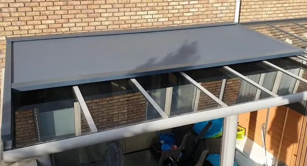 Zonwering op het dak van een overkapping, van onderen gezien, naast glazen dakplaten